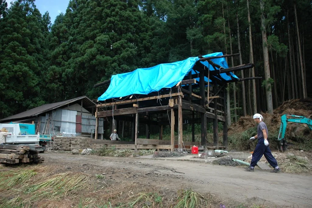 Timber frame of the Hakuba kominka under temporary covering during renovation