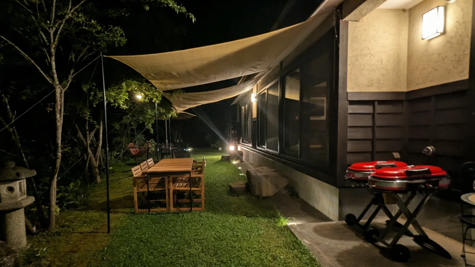 Garden dining and barbecue area illuminated at night at Rental Farmhouse Tamaki