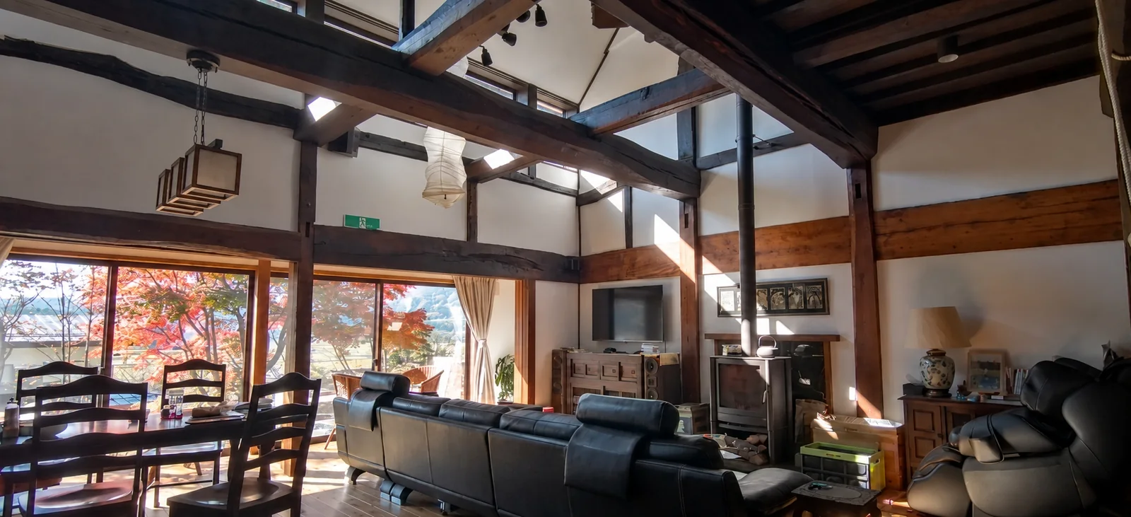 Open-plan living and dining room with original timber beams and autumn views at Rental Farmhouse Tamaki